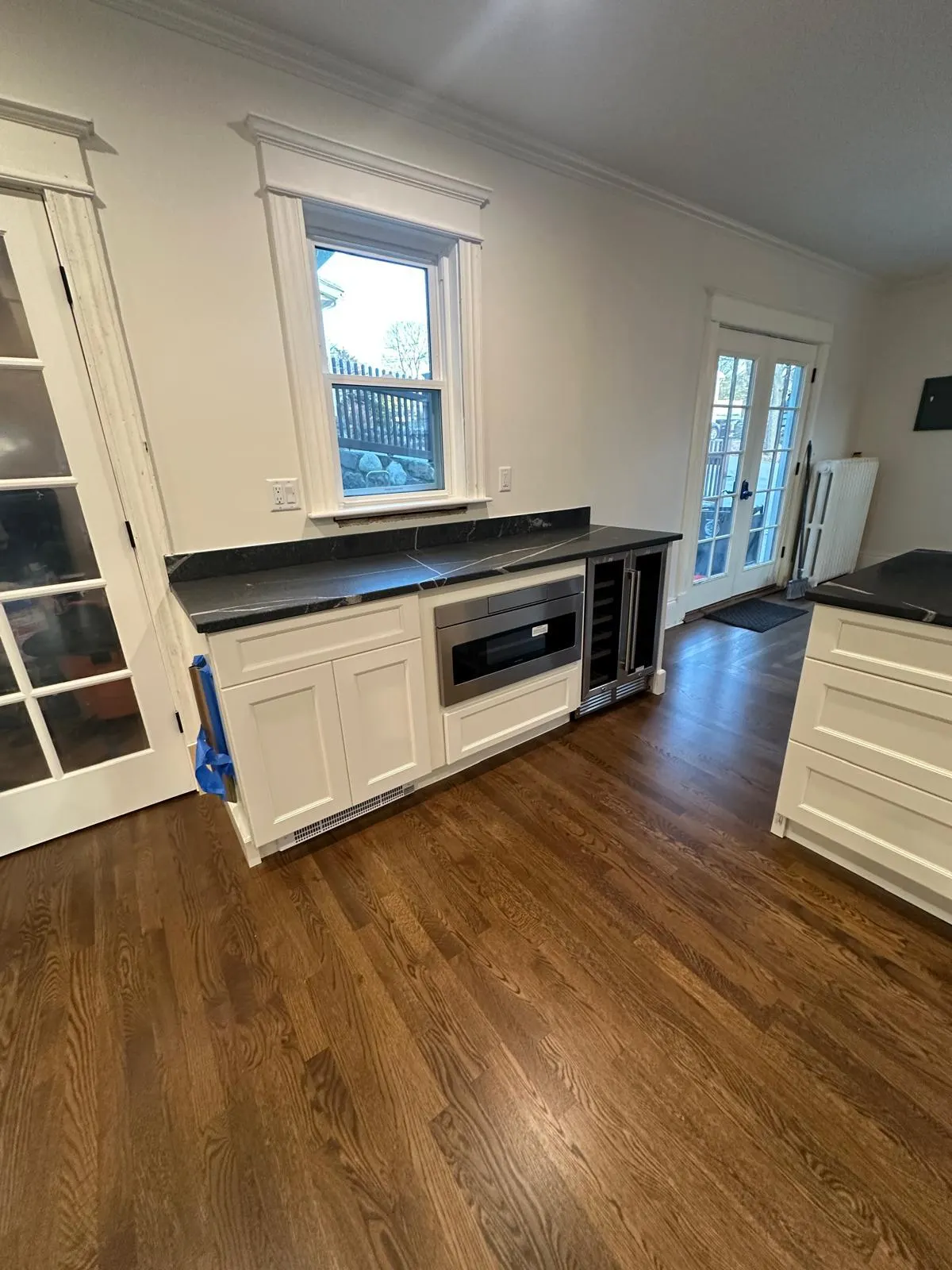 Kitchen cabinet run with built-in wine fridge over a hardwood floor