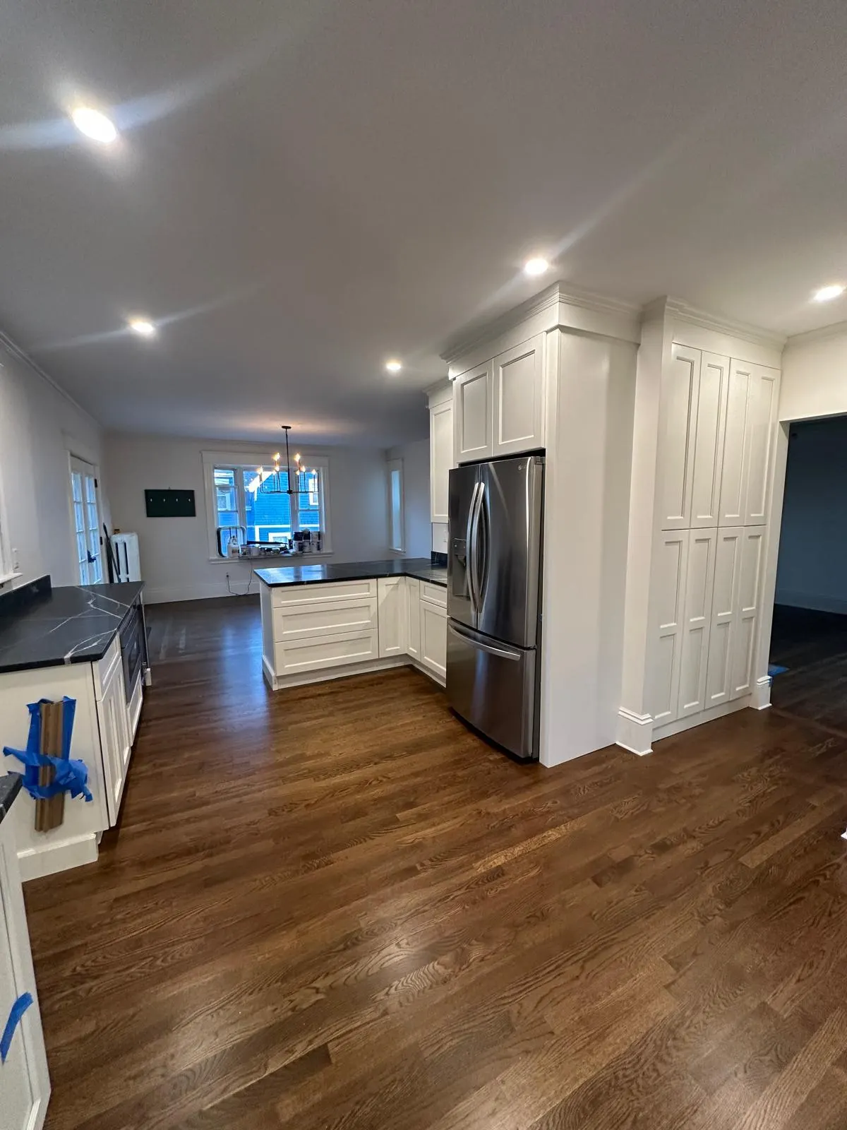 Open kitchen with white cabinets, island and hardwood floor