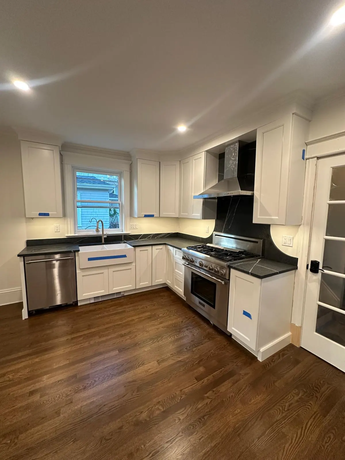Kitchen with white shaker cabinets, black countertops and hardwood floor